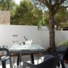 Tavolo all'aperto con quattro bicchieri di vino, circondato da alberi e un muro bianco basso.