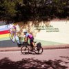 Ciclista su strada accanto a un murale colorato.