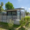 Una piccola casa prefabbricata con veranda in un campeggio verde.