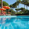 Piscina con ombrelloni arancioni e alberi.