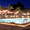 Piscina illuminata di sera con palme e luci decorative.