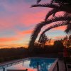 Piscina al tramonto con cielo arancione e palme.