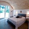 Camera con letto matrimoniale sotto un soffitto a volta, porta finestra aperta sul giardino.