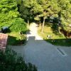 Vista dall'alto su un sentiero accanto a una casa con tetto rosso e alberi circostanti.