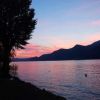 Un lago al tramonto con montagne scure e un cielo dai colori rosa e blu.