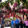 Un arco decorato con fiori rosa e gialli, sotto cui passano persone.