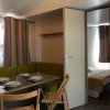 Sala da pranzo con tavolo apparecchiato e sedie pieghevoli, porta aperta su camera da letto.
