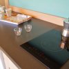 Piano cucina con fornello a induzione, caffettiera, tazzine e vassoio.