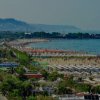 Lungomare con spiaggia affollata e palme.