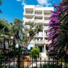 Facciata di un hotel tra alberi e fiori.