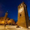 Torre dell'orologio in una piazza di sera.