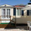 Casa mobile con terrazza, ombrellone e sedie su un patio.