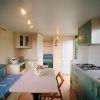 Interno di una casa mobile con cucina, tavolo, divano e finestre luminose.
