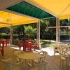 Tavolini e sedie di plastica sotto un tendone giallo in un'area esterna coperta.