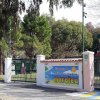Ingresso del Villaggio Camping Maratea con cancello verde e cartello di benvenuto.