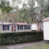 Una casa mobile con tetto rosso e finestre blu, circondata da alberi.