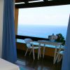 Interno con tende blu, tavolino e sedie su un balcone affacciato sul mare.