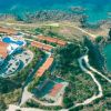 Vista aerea di una struttura turistica con piscine, edifici e costa.