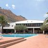Piscina e lettini, con palme e montagne in lontananza.