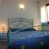 Camera con letto matrimoniale, copriletto blu a fiori, lampade sui comodini.
