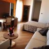 Camera con letto, divano, scrivania e accesso alla porta del balcone.