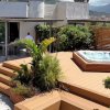 Jacuzzi su terrazza con piante e vista sui monti.