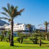 Prato verde e palme davanti a un edificio bianco.