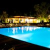 Piscina illuminata di notte con lettini attorno e vegetazione sullo sfondo.