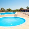 Due piscine all'aperto con lettini e ombrelloni blu sotto un cielo sereno.