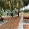 Area picnic con tavoli di legno e barbecue.