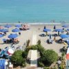 Ombrelloni blu su spiaggia vista dall'alto.