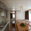 Interno di una casa mobile con cucina, divano angolare e finestre.