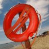 Salvagente rosso sulla spiaggia con ombrelloni.