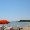 Spiaggia con ombrellone rosso e mare azzurro.