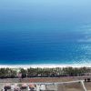 Vista aerea di una spiaggia con acqua blu e edifici residenziali sulla costa.