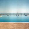 Piscina con vista sul mare, ombrelloni e sdraio sullo sfondo.