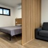 Camera con letto, separé in legno e divano grigio.