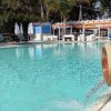 Piscina all'aperto con archi d'acqua e sdraio.