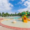 Piscina con un'area giochi d'acqua colorata e ombrelloni bianchi sullo sfondo.