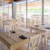 Ristorante con tavoli apparecchiati, vista esterna verso la piscina e il giardino.