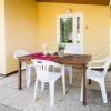 Tavolo da pranzo all'aperto con sedie bianche su una terrazza piastrellata.