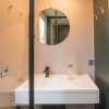 Bagno con specchio rotondo sopra un lavandino bianco e un diffusore di oli essenziali.