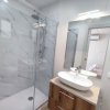 Bagno moderno con doccia in vetro e lavabo su mobile in legno, specchio ampio.