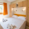 Camera da letto con letto matrimoniale, armadio in legno e finestra con tende arancioni.