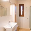 Bagno con doccia, lavandino e finestra stretta.