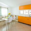 Cucina luminosa con mobili arancioni, tavolo da pranzo e seduta angolare.