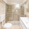 Un bagno con doccia con porte in vetro, lavabo moderno e wc sospeso.