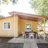 Una casa gialla con patio coperto, tavolo e sedie di plastica all'esterno.
