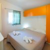 Camera con letto matrimoniale, armadio arancione e tende a righe. Asciugamani piegati sul letto.