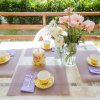 Tavolo apparecchiato con tazze floreali e vaso di fiori su un terrazzo.